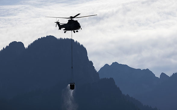 Ein Super Puma-Helikopter der Schweizer Armee tankt Wasser aus dem Montsalvens-See während der Wasserversorgung der Alpen und Wälder im August 2022.